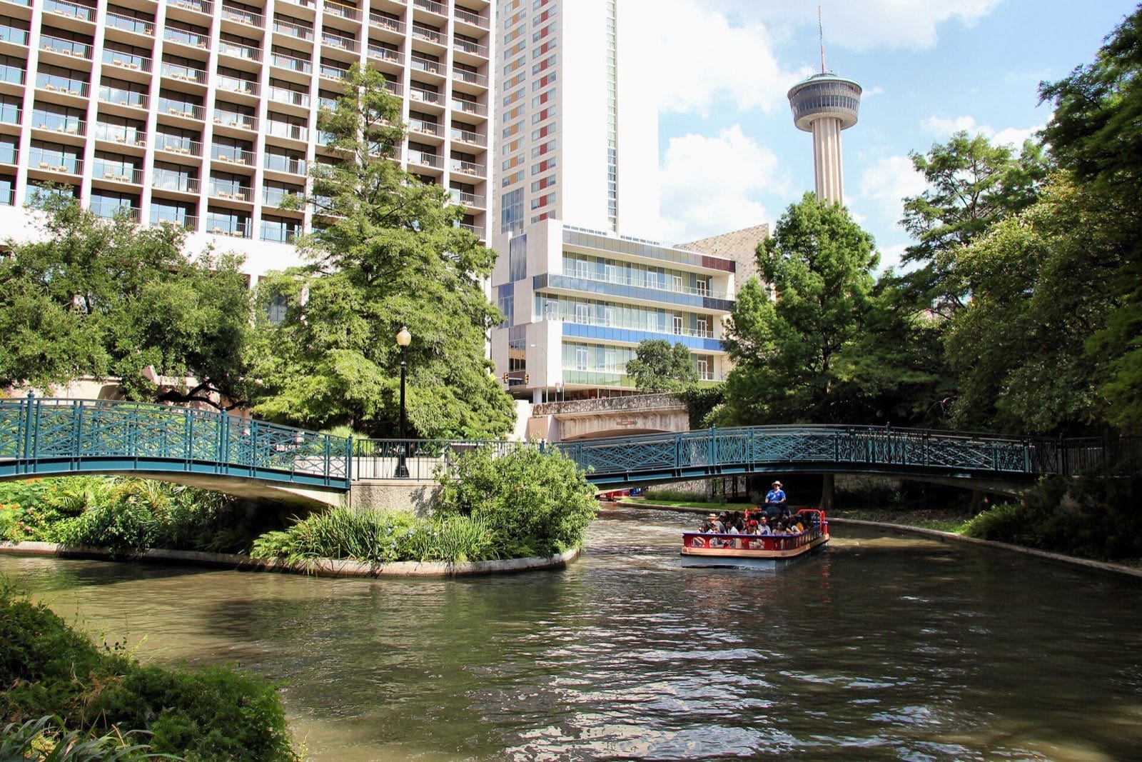 The San Antonio River Walk with a tour boat and the Tower of the Americas
