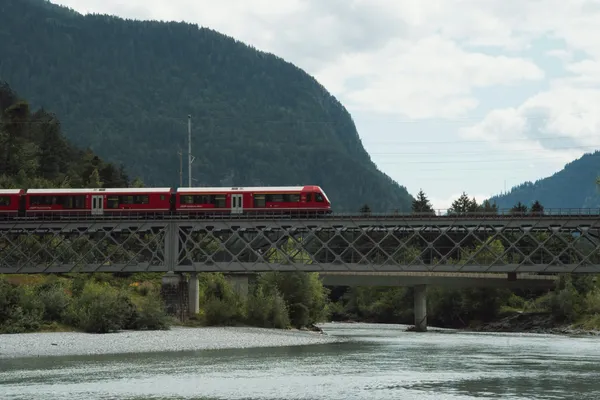 Roter Zug der Rhätischen Bahn auf einer Stahlbrücke bei Reichenau-Tamins in Graubünden, Schweiz