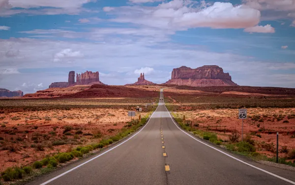 Gerade Landstraße durch das Monument Valley an der Grenze von Arizona und Utah, USA, mit roten Tafelbergen am Horizont